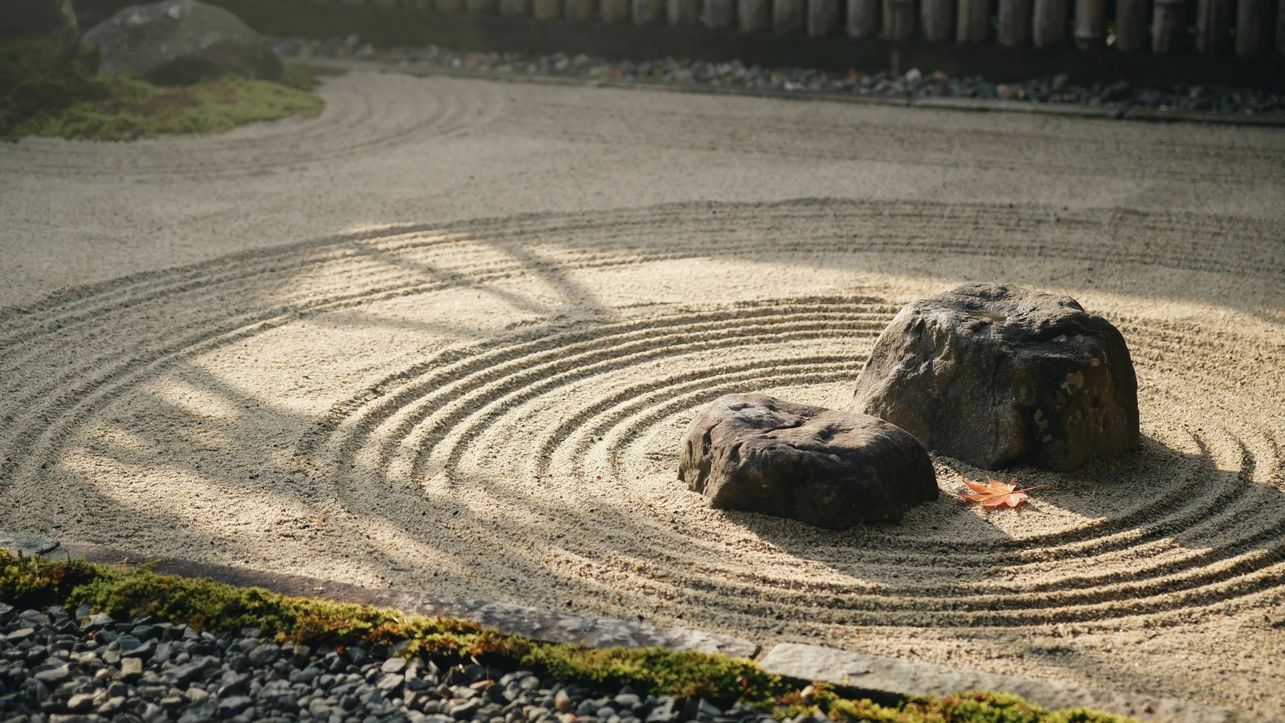 A raked gravel garden at dawn with two weathered stones